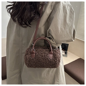Detail view of brown plush teddy fleece boston bag with leather straps and silver hardware
