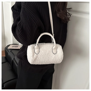 Detailed view of a white plush cylinder bag with leather handle and slim crossbody strap