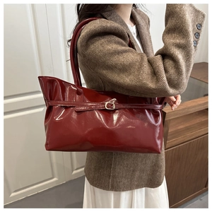 Détail du sac cabas en cuir verni rouge foncé avec boucle décorative élégante