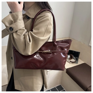 Détail du sac cabas brillant bordeaux avec boucle en métal sur un trench-coat kaki