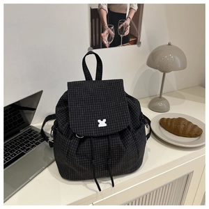 Detail eines schwarzen karierten Rucksacks mit Kordelzug und Puzzle-Abzeichen