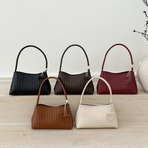 Sacs cabas en cuir tressé en cinq couleurs sur un présentoir en marbre chic