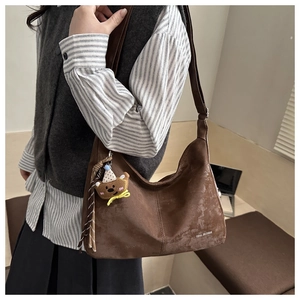 Detail of vintage brown suede crossbody bag with bear pendant and fringe decoration