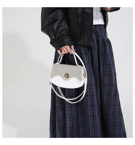 Detail of grey-white retro handbag featuring a circular metal twist lock and wavy pattern