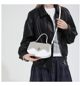 Detail of white and grey contrast handbag with wave flap and gold turn-lock buckle