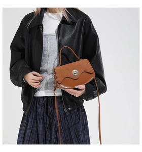 Close-up of vintage brown saddle bag featuring contrast textures and metal rotary buckle