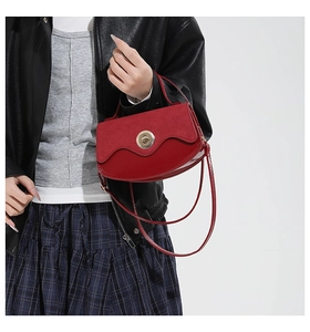 Detail of red saddle bag with suede texture and metallic gold twist-lock buckle
