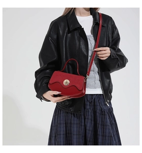 Detail shot of a red vintage shoulder bag with golden lock clasp and textured leather