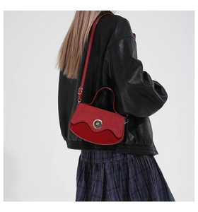 Detail of red vintage bag featuring a wavy suede flap and silver circular twist lock