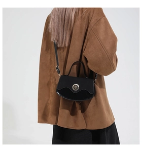 Detail of vintage black crossbody bag with gold lock worn by model for daily commute