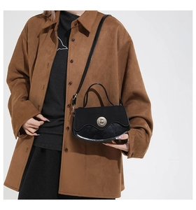 Close-up of black matte and patent leather crossbody bag with wave flap and metal twist lock