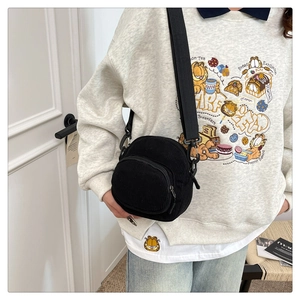 Detail of black corduroy crossbody bag with front zipper pocket and adjustable strap