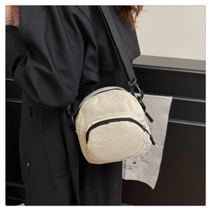 Detail of off-white corduroy crossbody bag showing adjustable nylon strap and texture