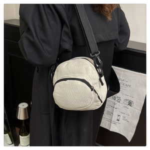 Detail of white corduroy shell bag texture with black shoulder strap and zipper