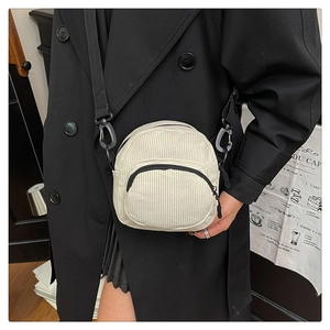 Detail view of corduroy shell crossbody bag with front zipper pocket and strap