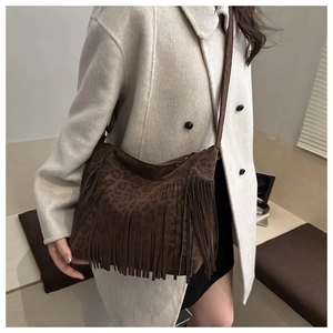 Détail d'un sac hobo à imprimé léopard avec franges et texture suédine porté par un modèle