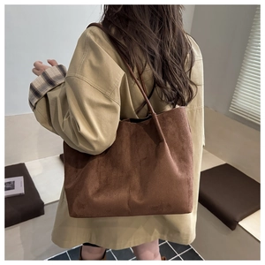 Detail of a large brown suede tote bag featuring high-quality matte texture and shoulder strap