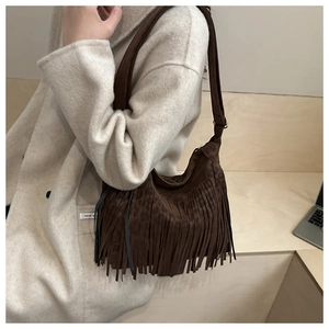 Détail du sac hobo en daim marron foncé avec de longues franges bohèmes et une large bandoulière