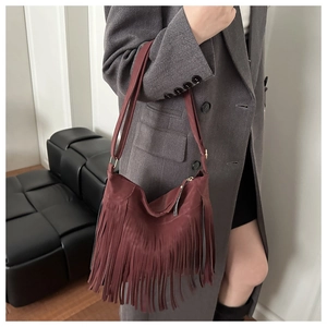 Détail d'un sac hobo bordeaux à franges en daim avec fermeture éclair dorée élégante