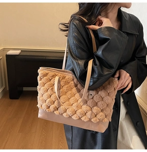 Detail of large tote bag showing unique beige honeycomb pom-pom texture and leather strap