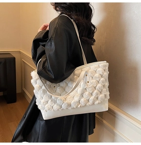 Detail of white plush bucket bag with fuzzy pom-pom texture and faux leather strap