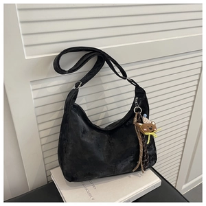 Close-up of black retro hobo bag with vintage texture and cute bear charm detail