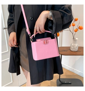 Détail du sac seau rose en cuir avec logo métallique rond et bandoulière réglable