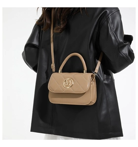 Detail of khaki quilted crossbody bag featuring a golden M logo and fine leather texture