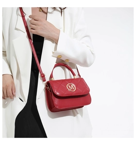 Detalle de bolso bandolera rojo acolchado con logo M dorado y costuras finas