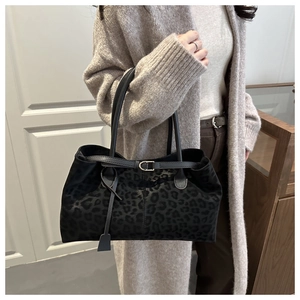 Detail of elegant black leopard print tote bag with fine handles and gold metal buckle