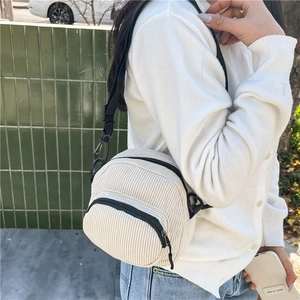 White corduroy crossbody bag with adjustable black strap and shell-shaped minimalist design