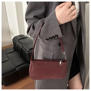Detail of dark burgundy baguette bag with leopard texture and silver zipper finish
