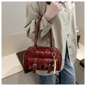 Dettaglio della borsa Boston in vernice bordeaux con doppie tasche e ciondoli di perle