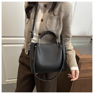 Detail of black lychee grain leather bucket bag with gold hardware and shoulder strap