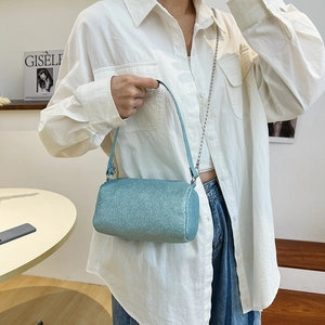 Sac cylindrique bleu scintillant avec chaîne argentée, porté par un mannequin en mode