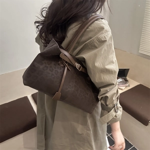 Brown leopard print tote bag with long straps worn by a model in a minimalist setting