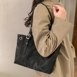 Vintage black oversized tote bag with silver eyelets shown on a model in a trench coat