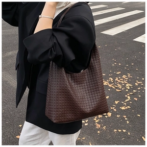 Detail of dark brown woven tote bag showing premium synthetic leather texture on model