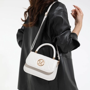 White quilted crossbody bag with gold M logo on a model in a black leather jacket