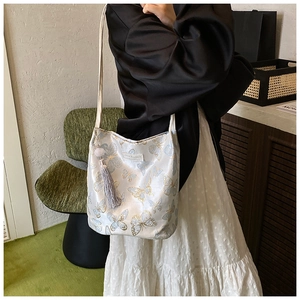 Detail of white satin shoulder bag with blue butterfly prints and tassel charm