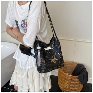 Détail du grand cabas noir à imprimé papillon doré avec pompon blanc et pochette