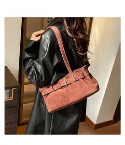 Detail of brick red suede shoulder bag featuring decorative metal buckles and retro style