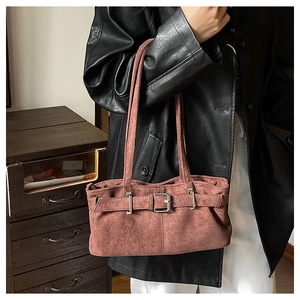 Detail of vintage brick red suede shoulder bag with decorative metal buckle and strap