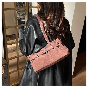 Detail view of brick red suede shoulder bag with silver buckle on female model