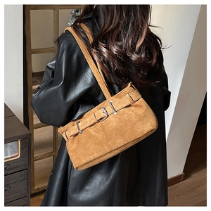 Detail of vintage brown suede shoulder bag with three silver buckle straps on the side