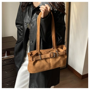 Close-up of brown suede underarm bag with vintage metal buckle and long shoulder strap