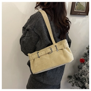 Model wearing a vintage beige suede underarm bag with a decorative metal buckle