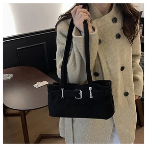 Detail of a black suede hobo bag featuring silver buckles on a shoulder strap design