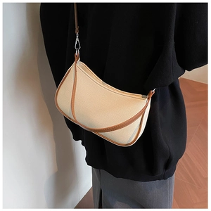 Close-up of a beige canvas crescent bag with brown faux leather trim and metal silver hooks