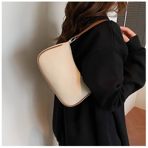Model draagt een minimalistische crème canvas halve maantas met bruine lederen afwerking